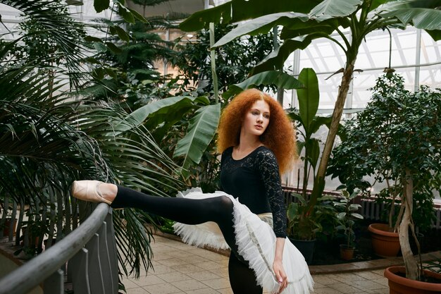 Bailarina joven bailando en un jardín botánico interior