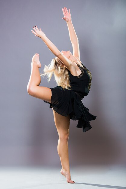 Bailarina joven y elegante posando sobre fondo gris