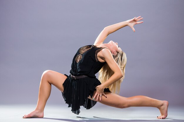 Bailarina joven y elegante posando sobre fondo gris