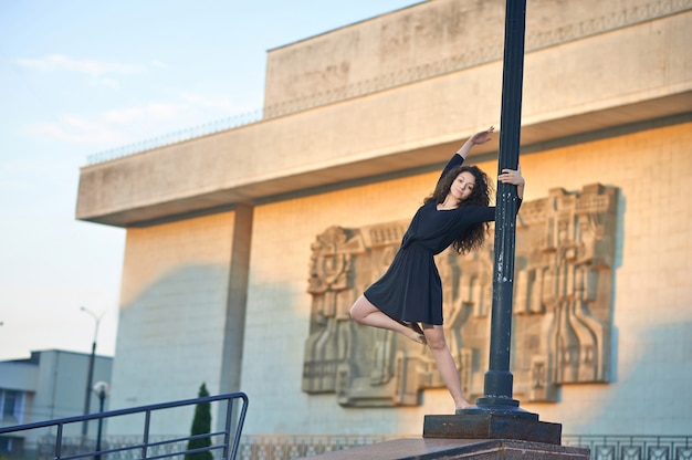 Bailarina en el pilar de la lámpara cerca de la fachada del edificio interesante.