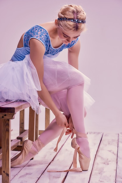 Bailarina profesional poniéndose sus zapatos de ballet.