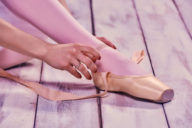 Bailarina profesional poniéndose sus zapatos de ballet.