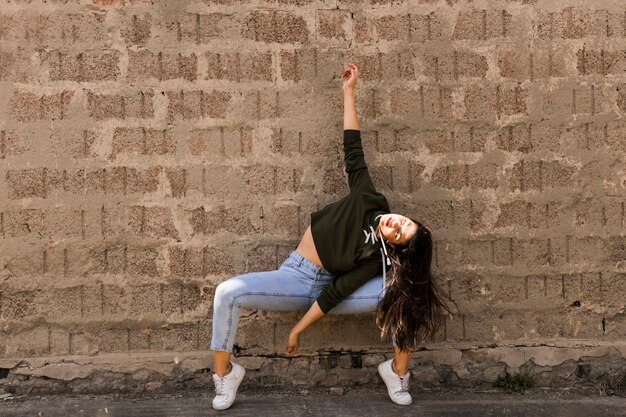 Bailarina de sexo femenino joven moderno que baila delante de la pared del grunge