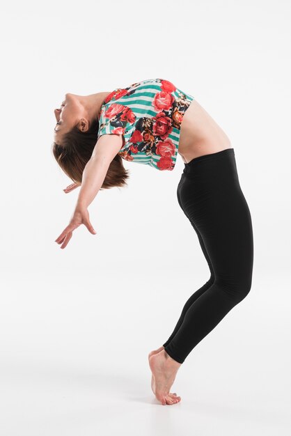 Bailarina de sexo femenino que realiza salto de la cadera aislado sobre el fondo blanco