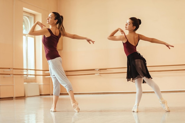 Bailarina y su instructora bailando mientras ensayan en el estudio de ballet