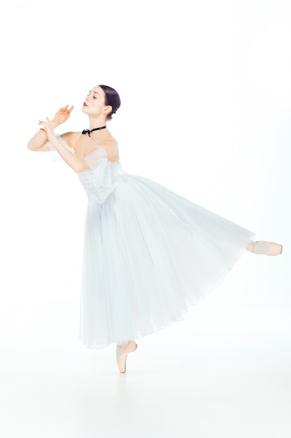 Bailarina en vestido blanco posando en zapatillas de punta