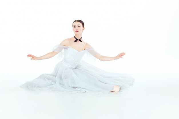 Bailarina en vestido blanco sentado, estudio.