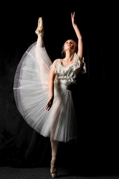 Bailarina en vestido tutú posando con la pierna arriba