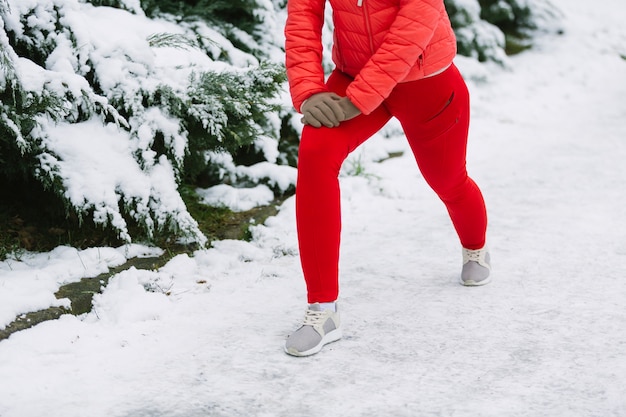 Baja sección de atleta femenina haciendo ejercicio en la nieve.