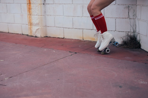 Baja sección de patinador femenino balanceándose sobre patines