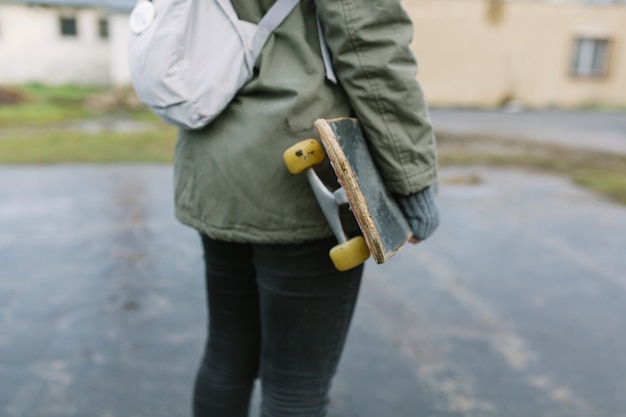 Foto gratuita baja sección de patinadora femenina de pie con patineta.