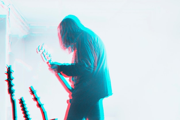 Bajista actuando en un concierto en efecto de exposición de doble color