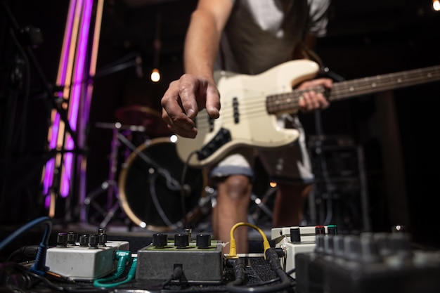 Bajista en un escenario con un conjunto de pedales de efectos de distorsión.