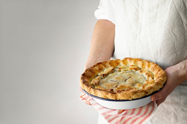 Baker sosteniendo un delicioso postre de tarta de cerezas recién horneadas