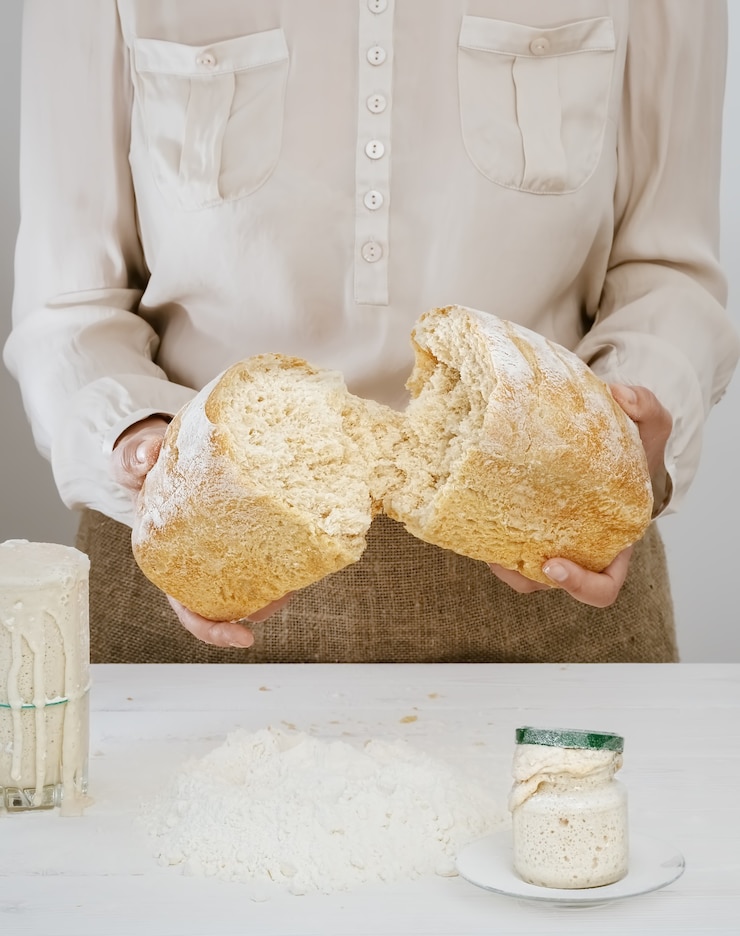 Foto gratuito baker tiene en sus manos un pan de masa madre recién horneado