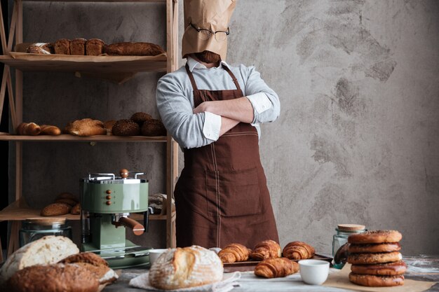 Bakerun panadero de pie en la panadería cerca del pan