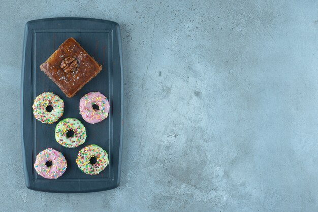 Bakhlava y donas en un tablero azul marino sobre superficie de mármol