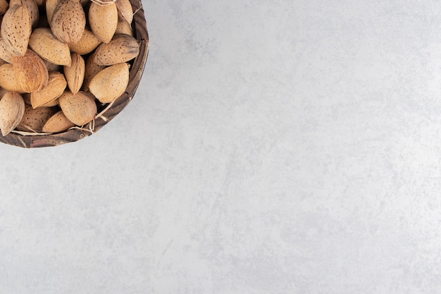 Un balde lleno de almendras en el balde, sobre la superficie de mármol