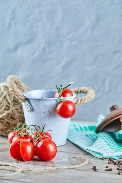 Foto gratuita balde de tomates y tomate medio cortado sobre mesa de madera