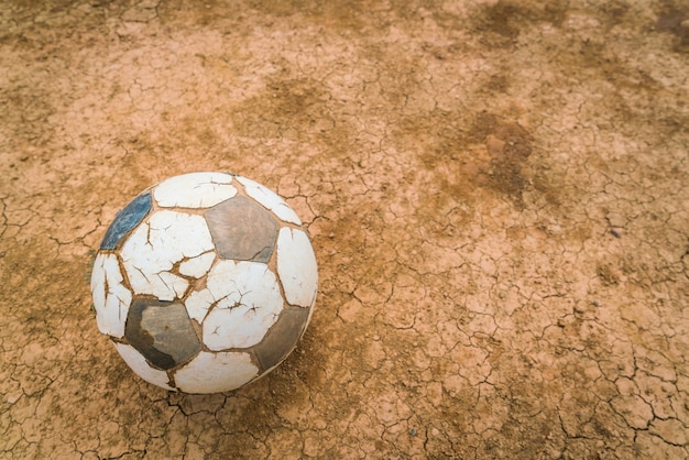 Balón de fútbol en seco y una textura tierra agrietada.