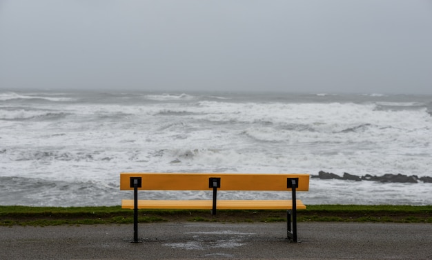 Banco en la playa rodeado por el mar bajo un cielo nublado durante la tormenta