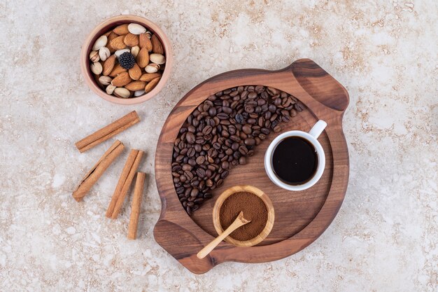 Bandeja de café junto a palitos de canela y un tazón pequeño de frutos secos variados