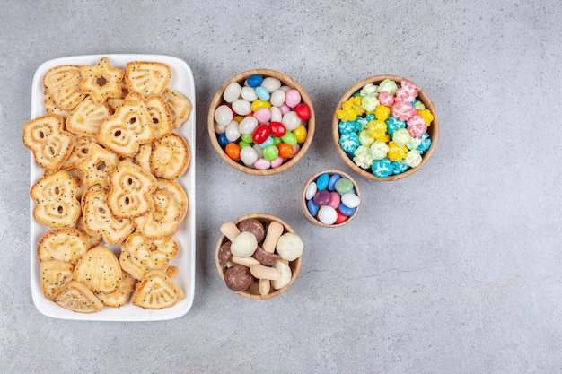 Una bandeja de chips de galleta junto a tazones de dulces y setas de chocolate en la superficie de mármol