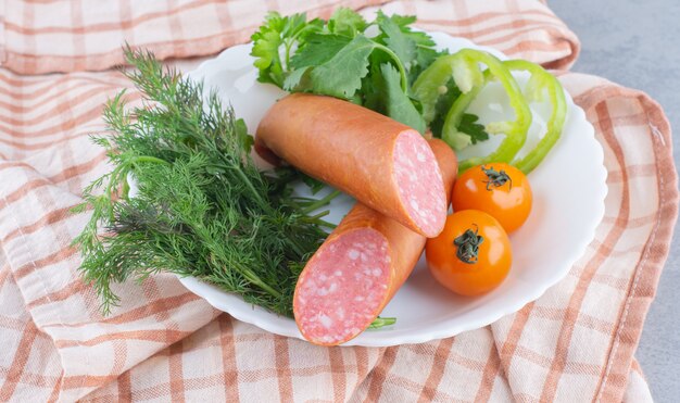 Bandeja de comida con delicioso salami, tomate, ensalada y verdura.