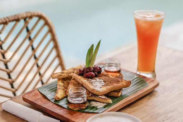 Bandeja de comida y galletas en una mesa de madera junto a un vaso de jugo y café