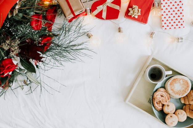 Bandeja con desayuno cerca de ramo y regalos