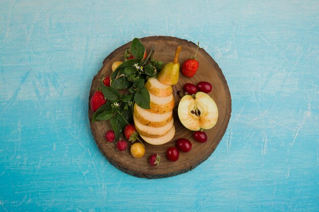 Bandeja de frutas redonda con peras, manzana y frutos rojos en el medio