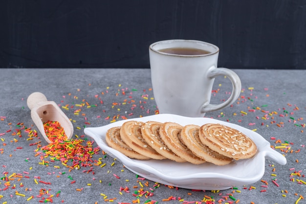 Una bandeja de galletas, una bola con caramelos y una taza de té.