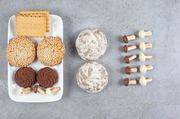 Una bandeja con galletas encima y al lado. con setas de chocolate alineadas sobre fondo de mármol. Foto de alta calidad