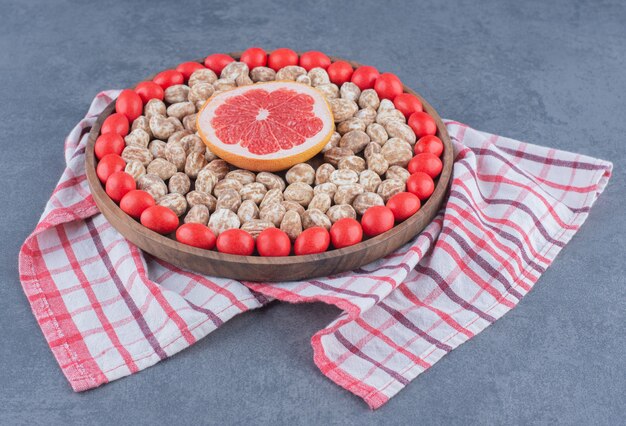 Bandeja llena de galletas y chicles con pomelo en el medio, sobre el fondo de mármol.