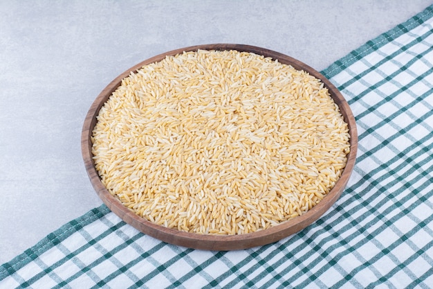 Bandeja de madera grande llena de arroz integral sobre superficie de mármol