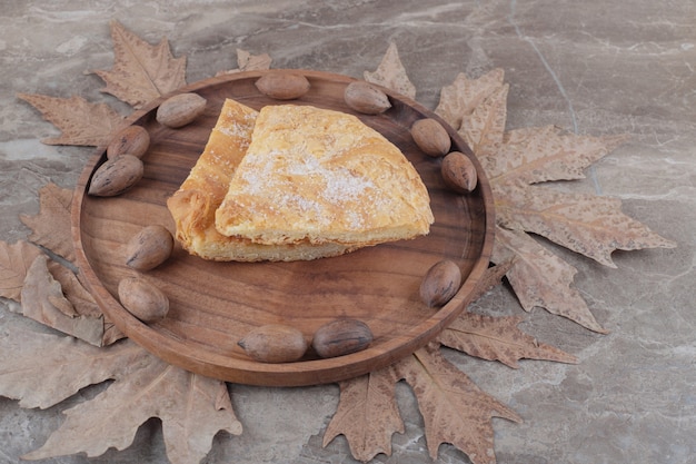 Una bandeja con nueces pecanas y rodajas de pan plano feseli en mármol