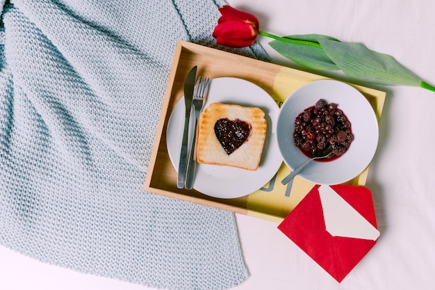 Foto gratuita bandeja con pan tostado con mermelada en forma de corazón y bayas.