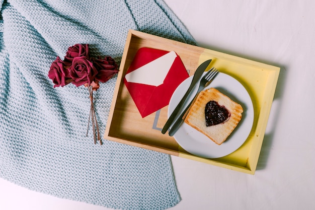 Bandeja con pan tostado con mermelada en forma de corazón y sobre