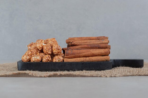 Bandeja pequeña con pilas de palomitas de maíz dulces y cortes de canela sobre mesa de mármol.