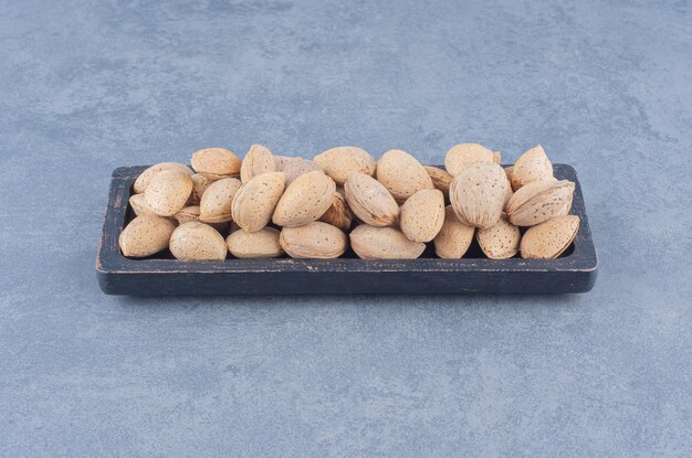 Una bandeja de sabrosas almendras, sobre el fondo de mármol.