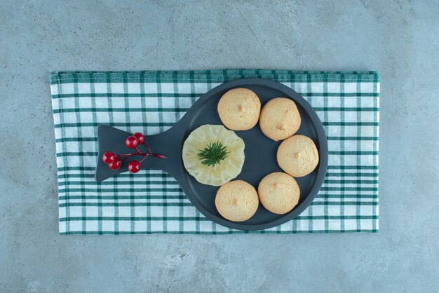 Una bandeja para servir con galletas y adornos navideños sobre una toalla sobre la superficie de mármol