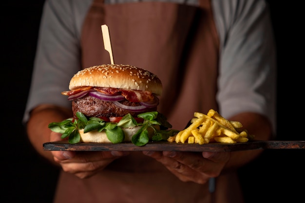 Bandeja de sujeción masculina vista frontal con hamburguesas y papas fritas