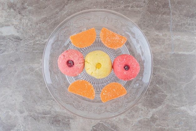 Foto gratuita bandeja de vidrio con galletas y dulces de gelatina en la superficie de mármol