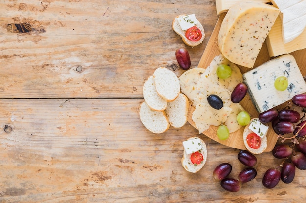 Foto gratuita bandejas de queso con uvas y pan en escritorio de madera