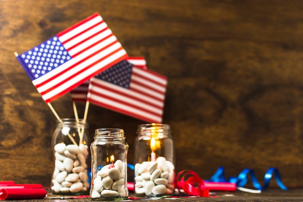 Bandera estadounidense de Estados Unidos y velas encendidas en el tarro de caramelos blanco en el escritorio de madera