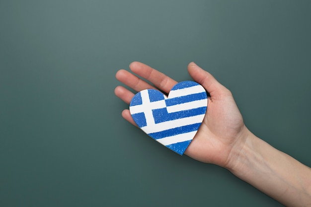 Bandera de grecia en forma de corazón sostenida en las manos