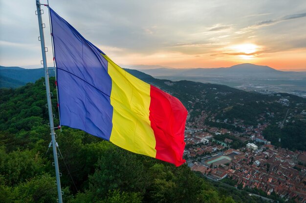 Bandera nacional en la cima de la colina en Brasov al atardecer Rumania