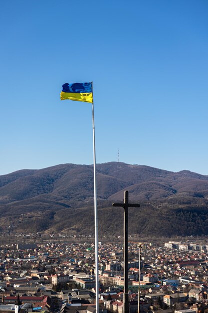 Bandera ucraniana y cruz en el fondo de las montañas