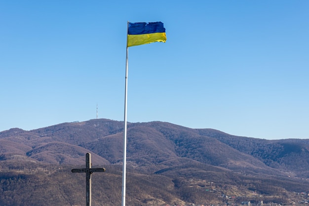 Bandera ucraniana y cruz en el fondo de las montañas