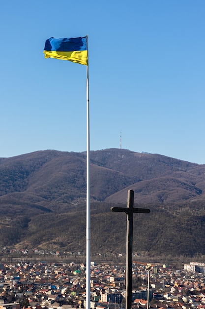 Bandera ucraniana y cruz en el fondo de las montañas